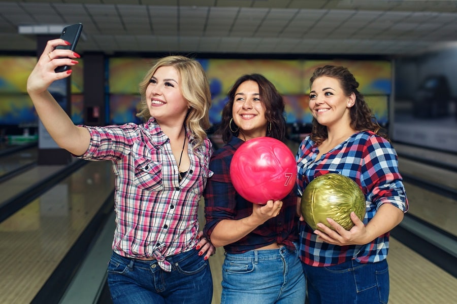 happy girlfriends take selfie with smartphone at bowling club
