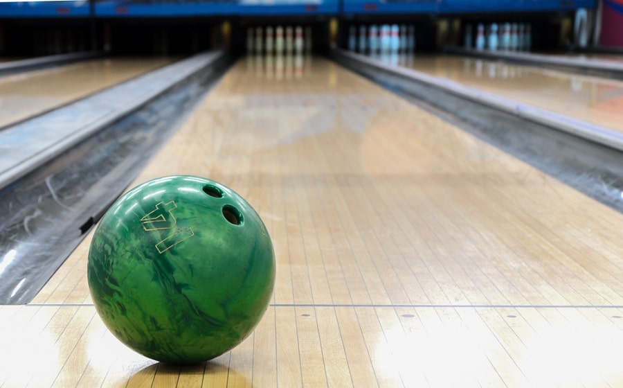 Close-up of green bowling ball against background of empty lanes in bowling alley
